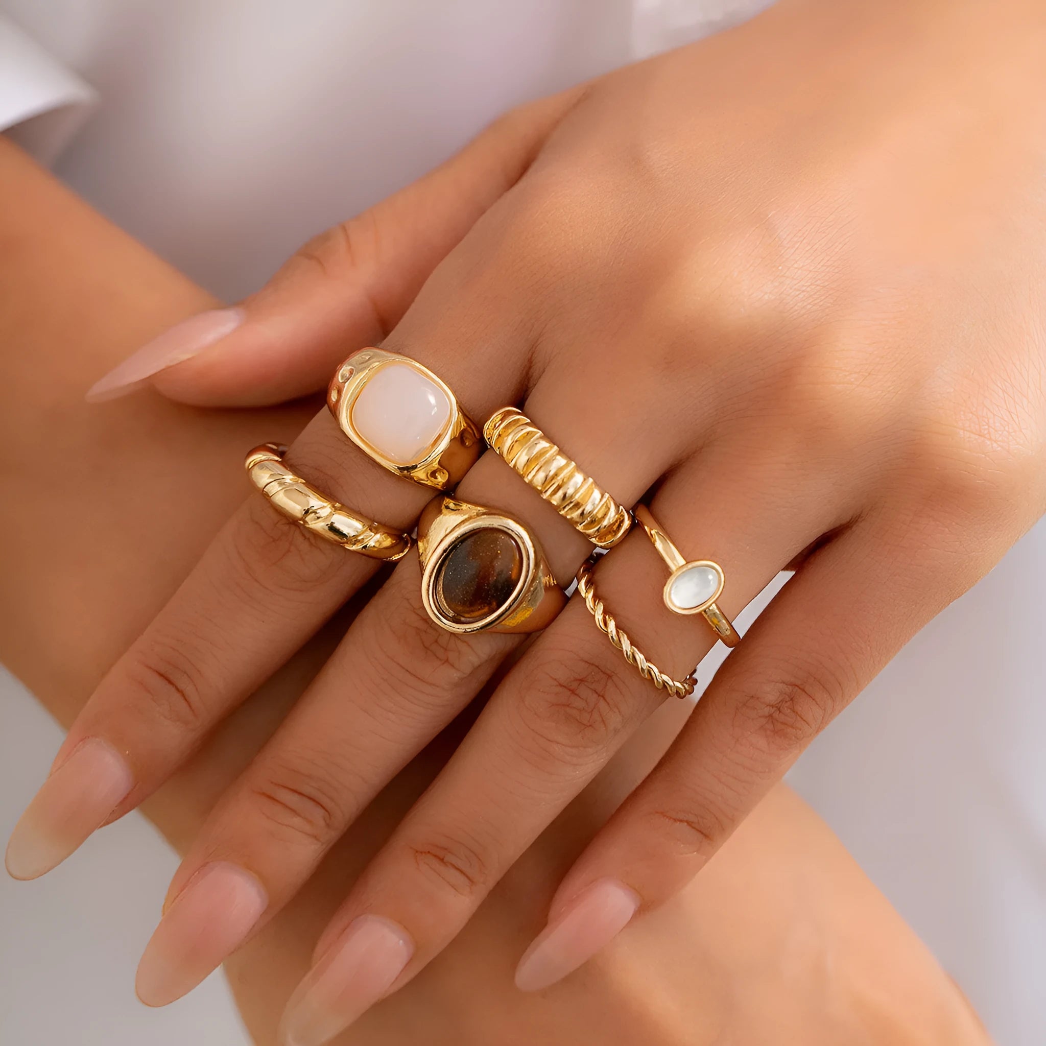 Six light gold alloy rings with irregular geometric shape, electroplated finish, on display