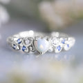 White alloy women's ring with a heart shape, floral detailing, and opalescent peach ocean design.