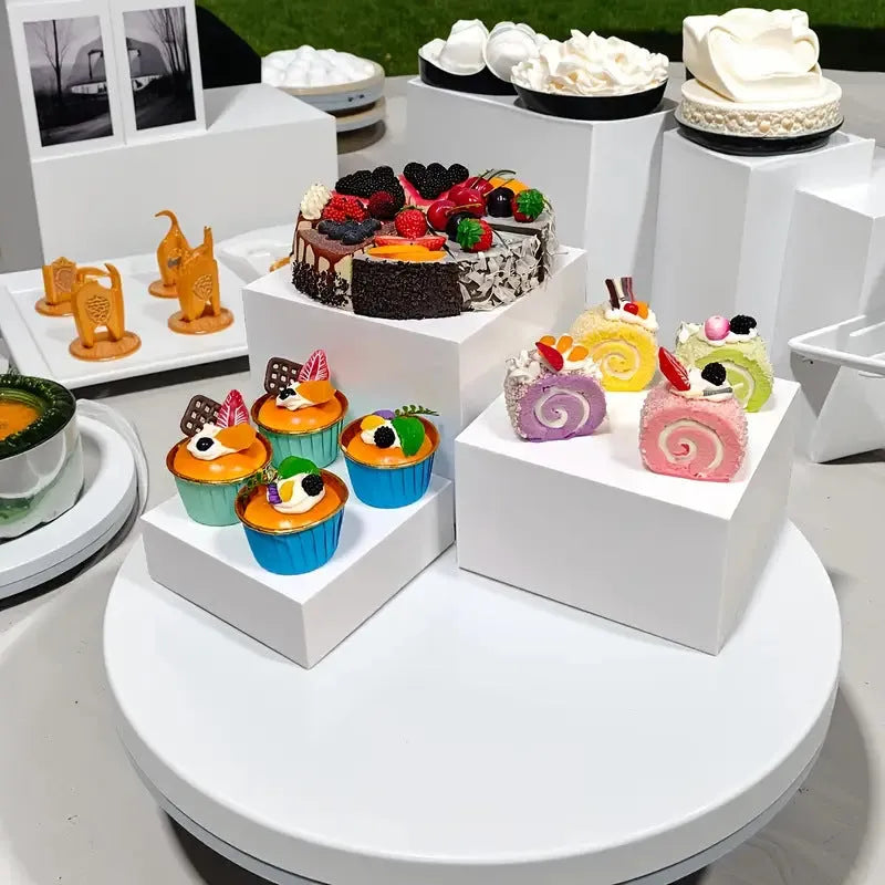 White and clear plastic modular six-piece suit cube dessert display stand on a desktop.