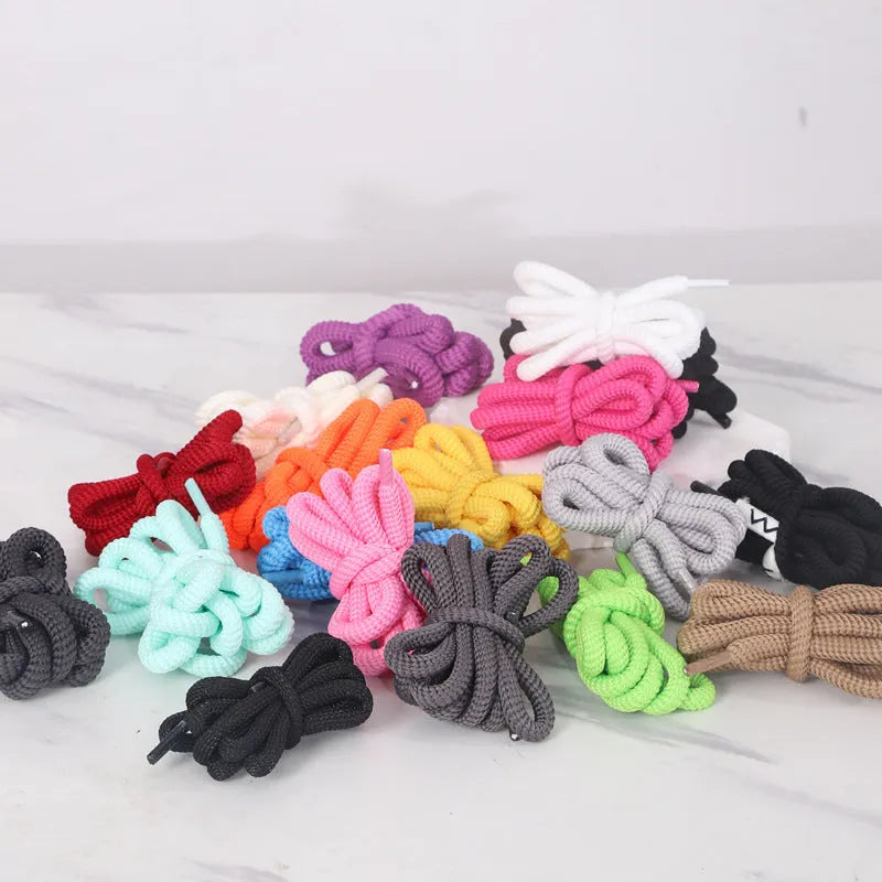 A pair of black oval shoelaces with round profile next to colour swatches showing pink, blue, gray, and orange options.