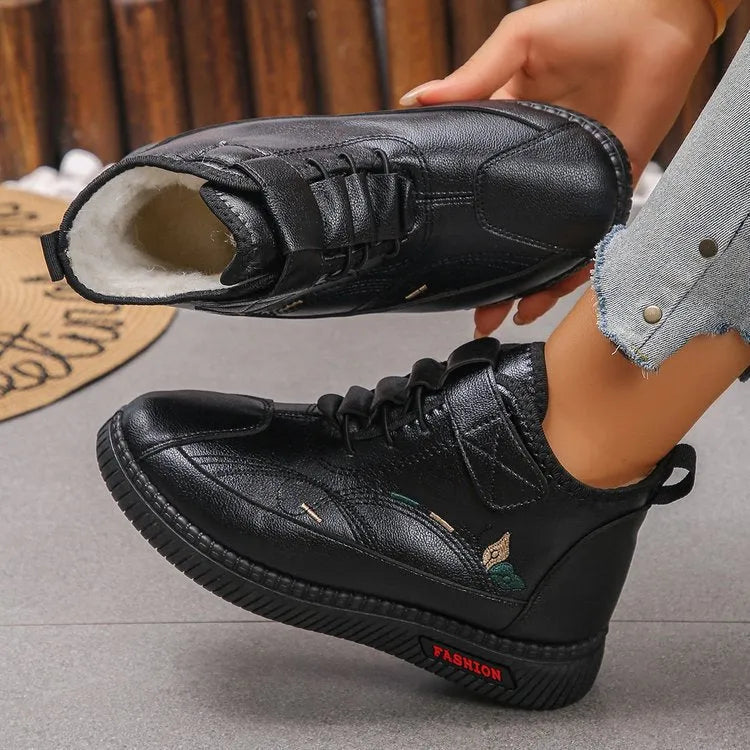 Women's black velvet slipper with non-slip rubber sole and hollow out design on a wooden floor.