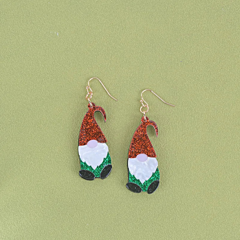 Close-up of a pair of Santa Claus cartoon acrylic earrings in red, green, and red-and-green hat designs on a light background
