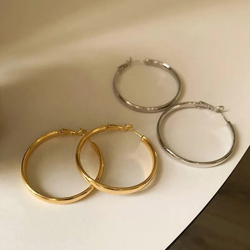 A pair of large gold-coloured circular metal earrings with a 40mm diameter on a white background.