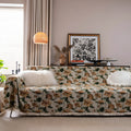 American country style jacquard patterned sofa cover in a green colourway draped over a sofa.