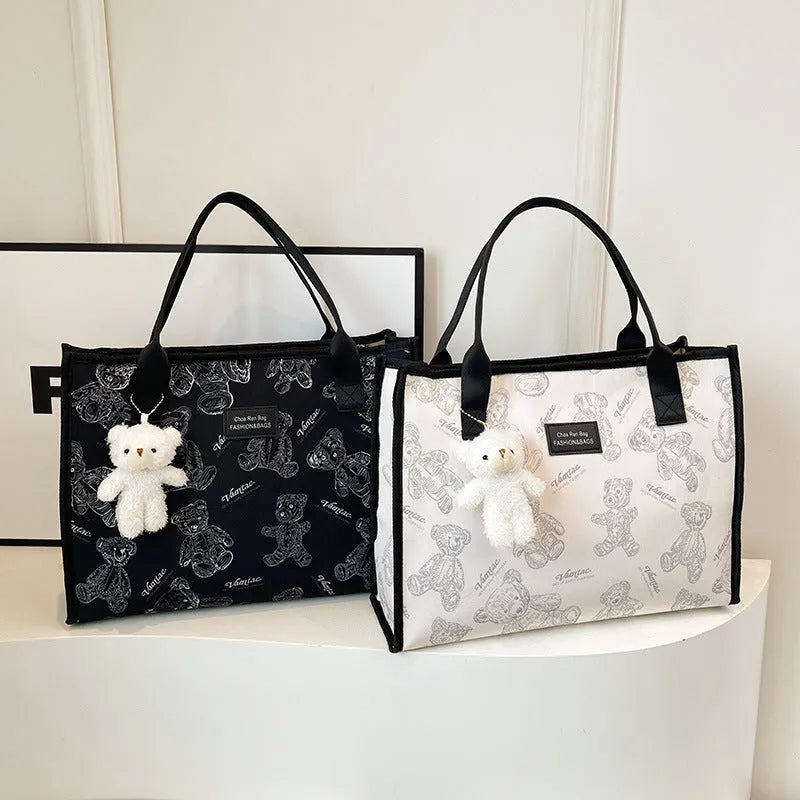 Women's black canvas tote bag with rhombus pattern showing horizontal square shape and shoulder strap