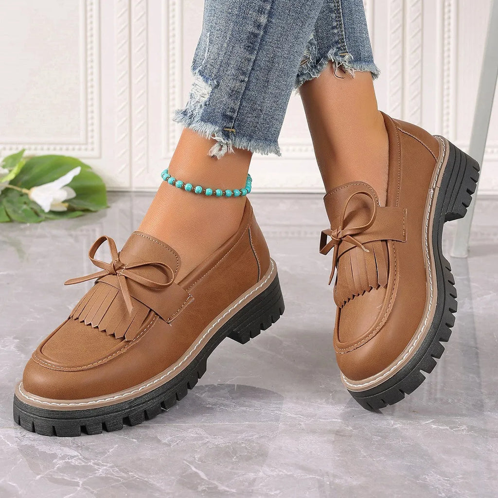 Black plus size women's loafer with tassel decoration and a bowknot on a low chunky heel.