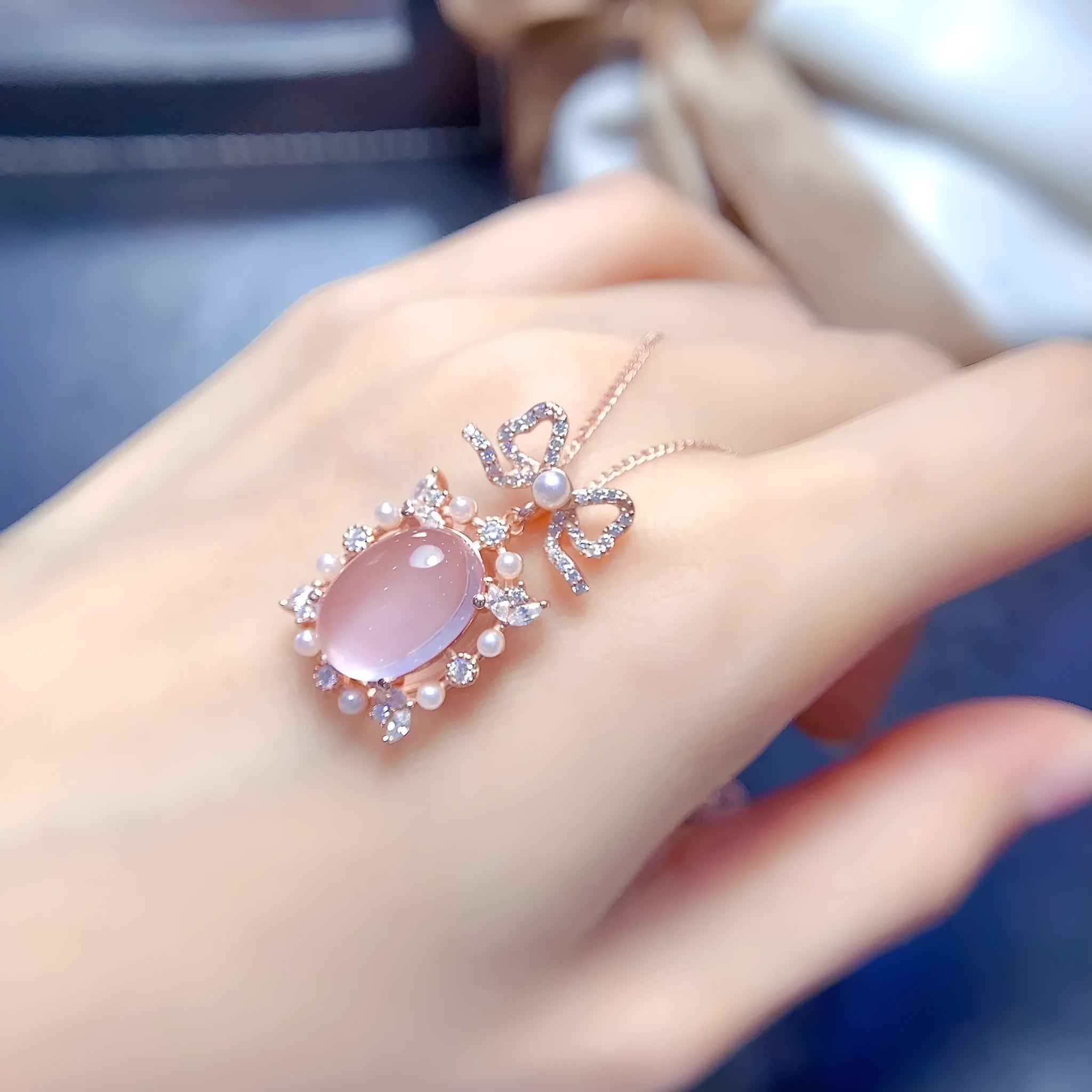 Geometric silver alloy pendant with pink rose quartz crystal and rose gold plating on a chain.