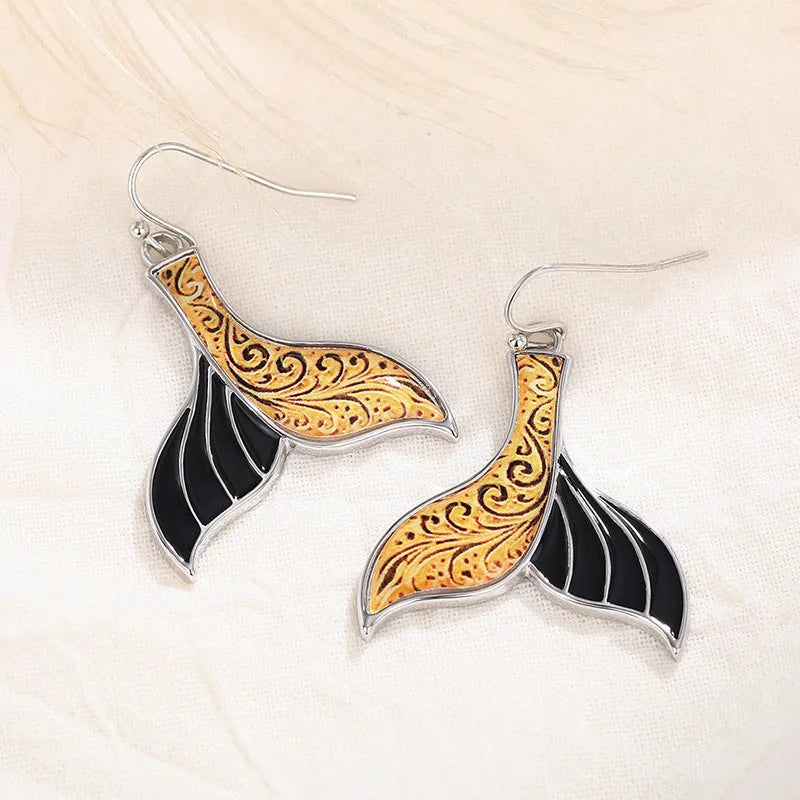 Close-up of women's retro fishtail earrings with a whale design in white gold colour.