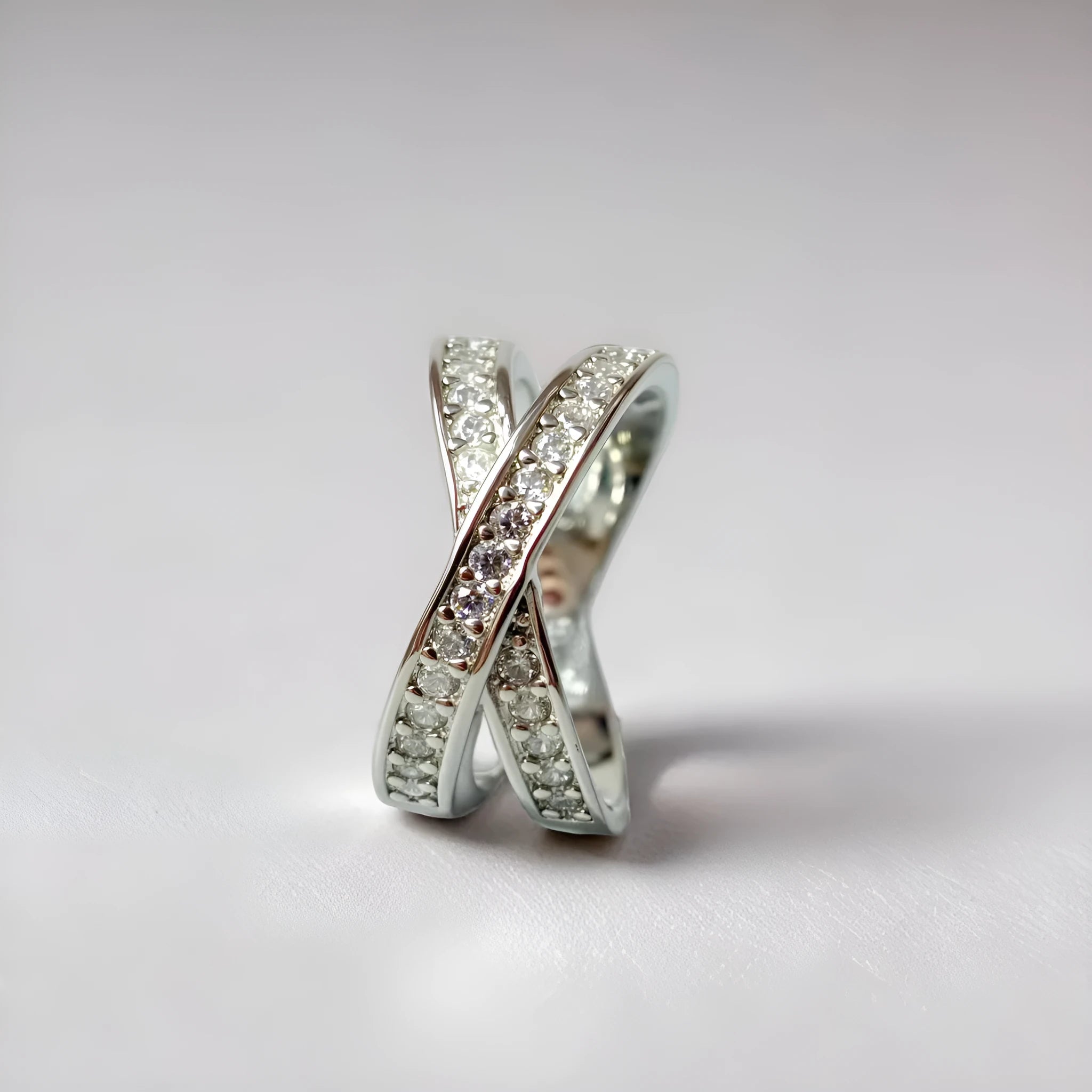 Copper metal cross ring with micro-inlaid zircon stones in silver electroplated finish showing geometric heart-shaped design