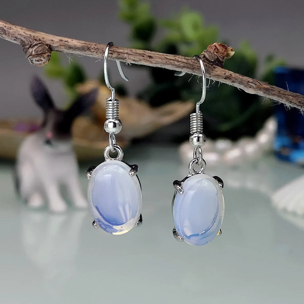 A pair of retro opal earrings with a moonstone eardrop and cross design in electroplated alloy.