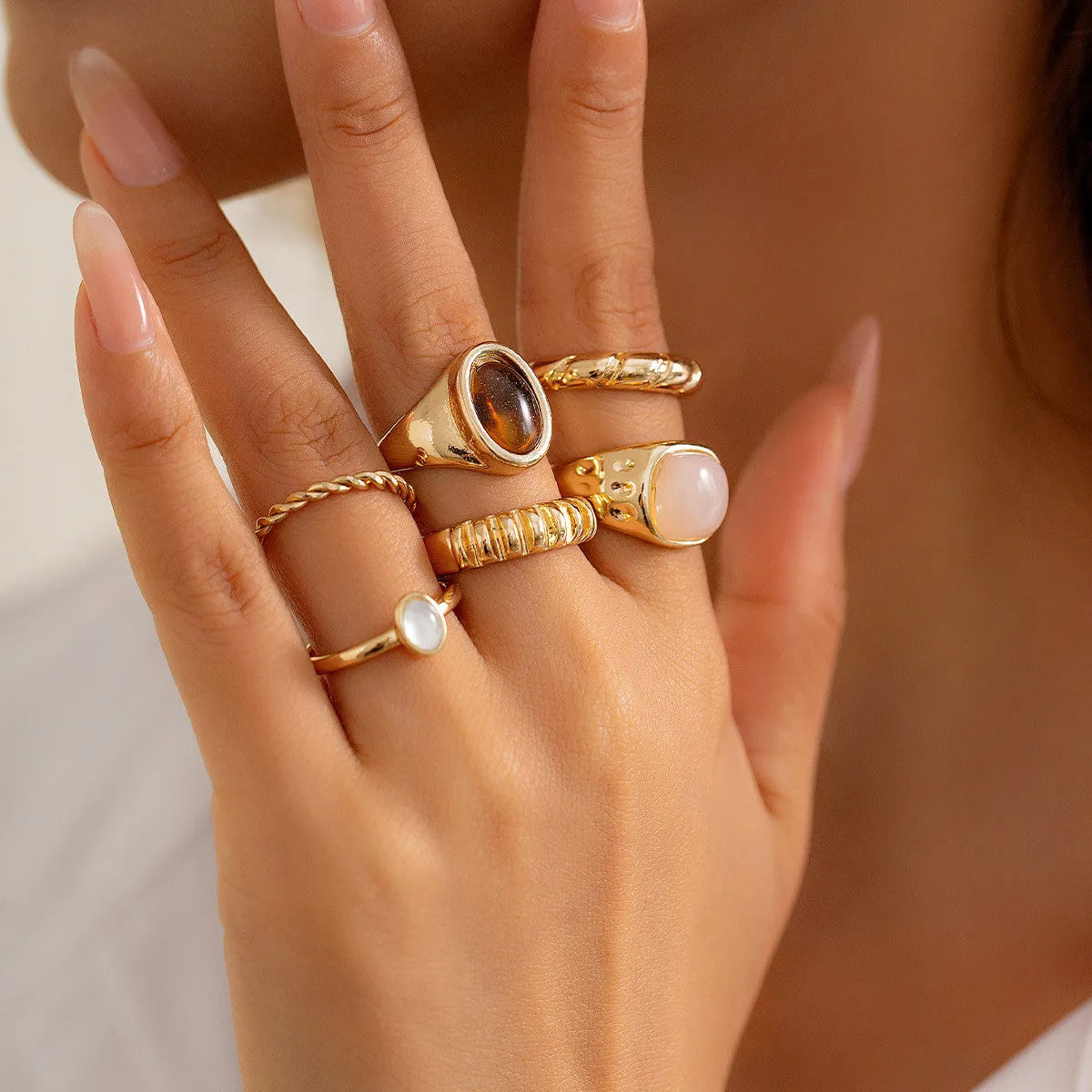 Six light gold alloy rings with irregular geometric shape, electroplated finish, on display