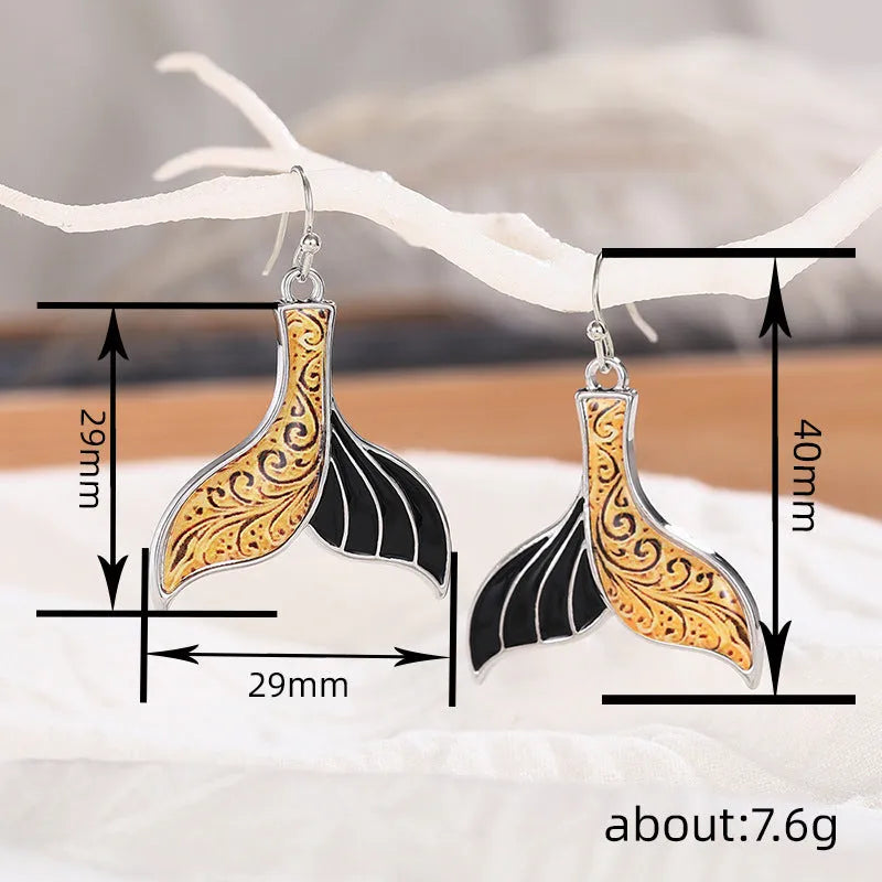 Close-up of women's retro fishtail earrings with a whale design in white gold colour.