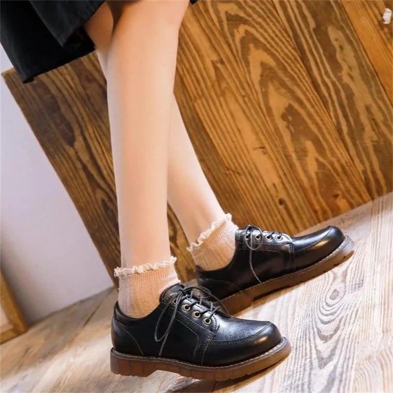 Women's black preppy style low-heel Mary Jane shoe with front lace-up and round toe on a white background.