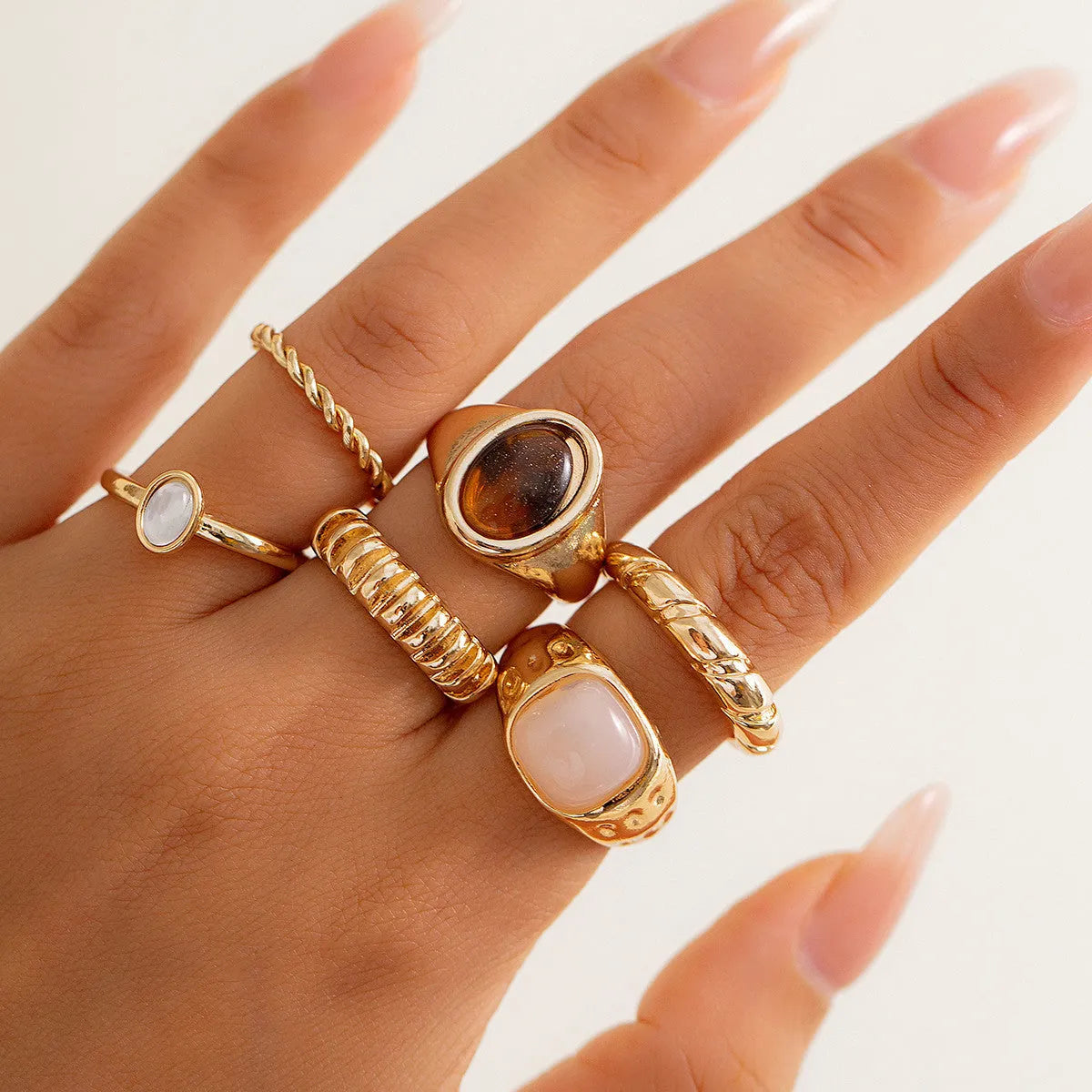 Six light gold alloy rings with irregular geometric shape, electroplated finish, on display