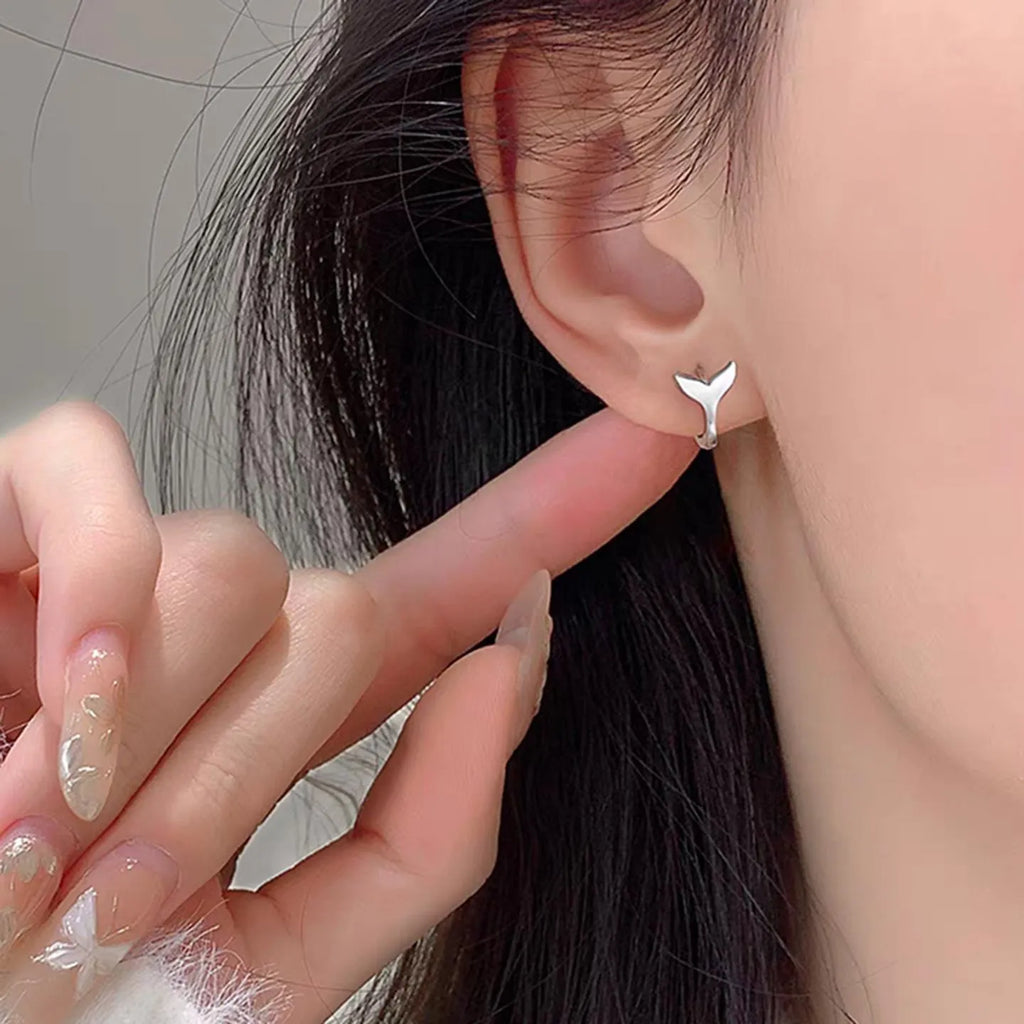 A pair of simple women's fishtail earrings with an electroplated finish in white gold or yellow gold colour.