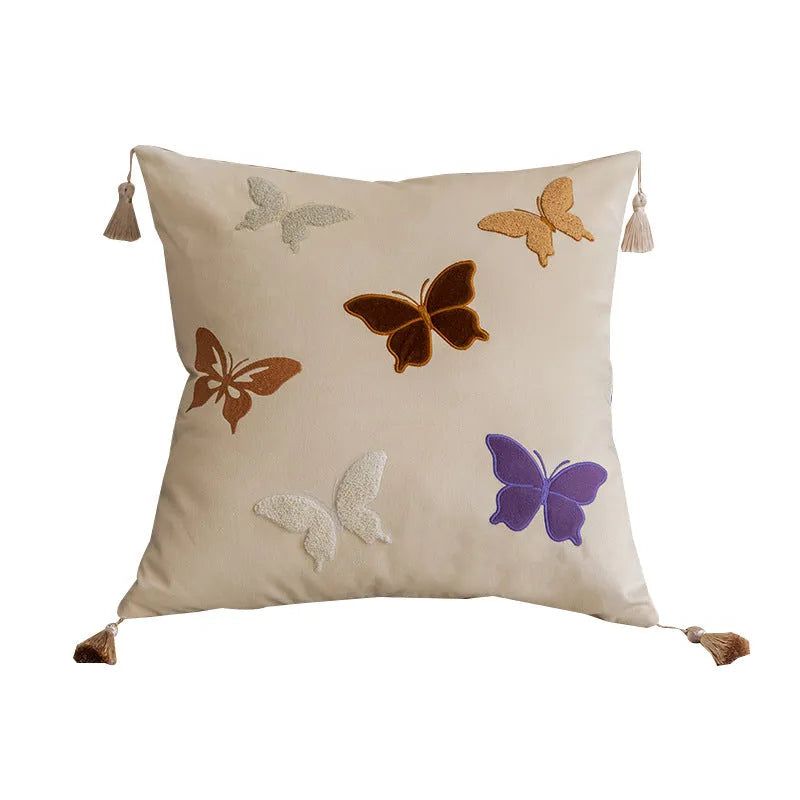 Square decorative cushion with embroidered butterfly pattern in beige, black, or purple colours.