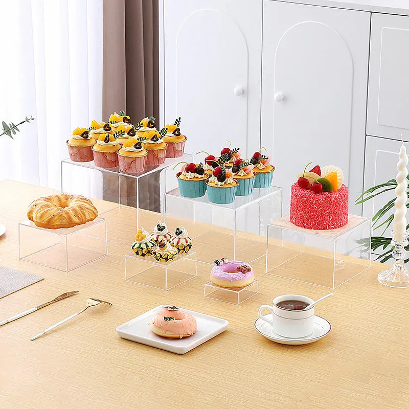 White and clear plastic modular six-piece suit cube dessert display stand on a desktop.
