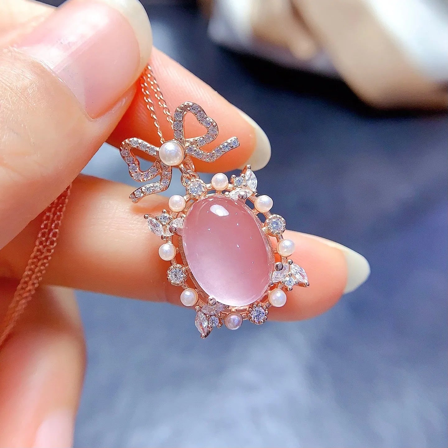 Geometric silver alloy pendant with pink rose quartz crystal and rose gold plating on a chain.