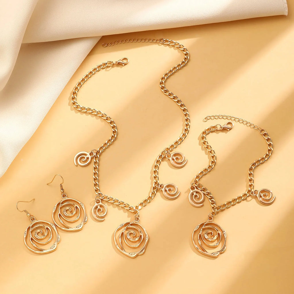 Gold spiral donut necklace, bracelet, and ear hooks set for women on a plain background.