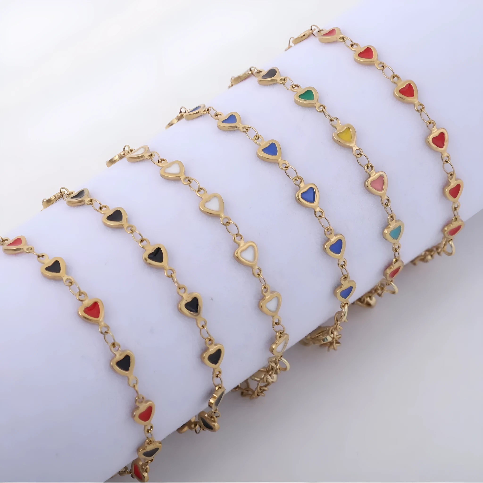 Stainless steel bracelet with heart charm in 18K gold plating, shown in adjustable length on a wrist.