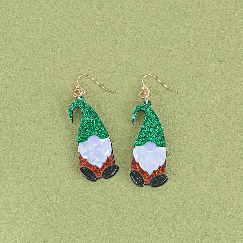 Close-up of a pair of Santa Claus cartoon acrylic earrings in red, green, and red-and-green hat designs on a light background