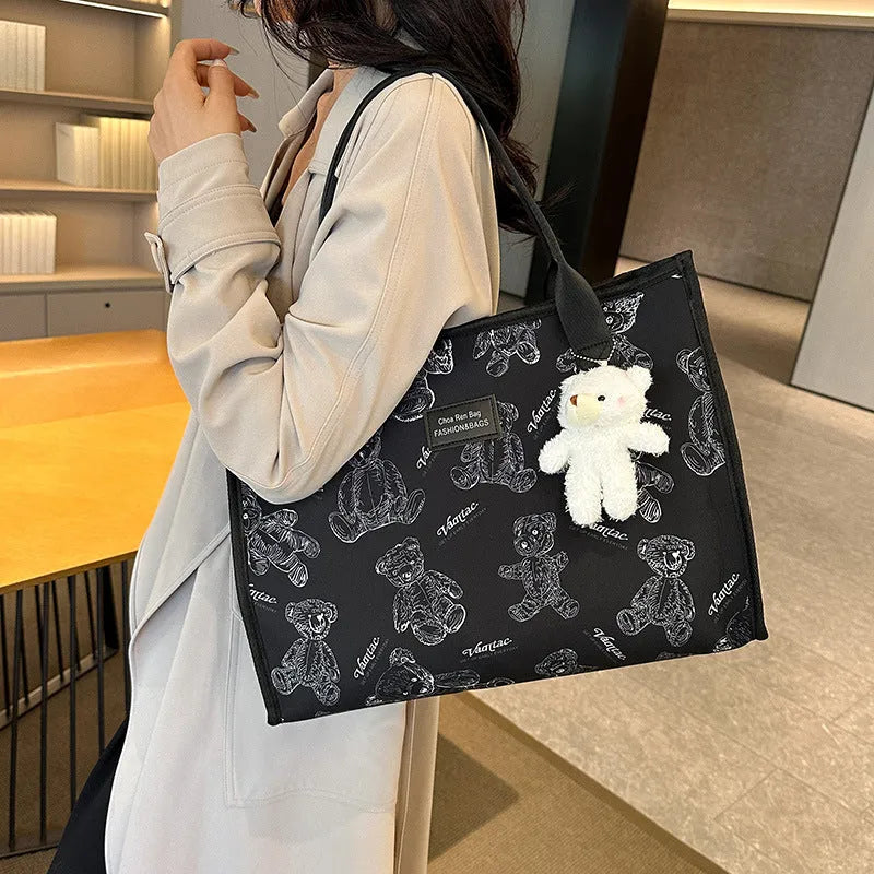 Women's black canvas tote bag with rhombus pattern showing horizontal square shape and shoulder strap