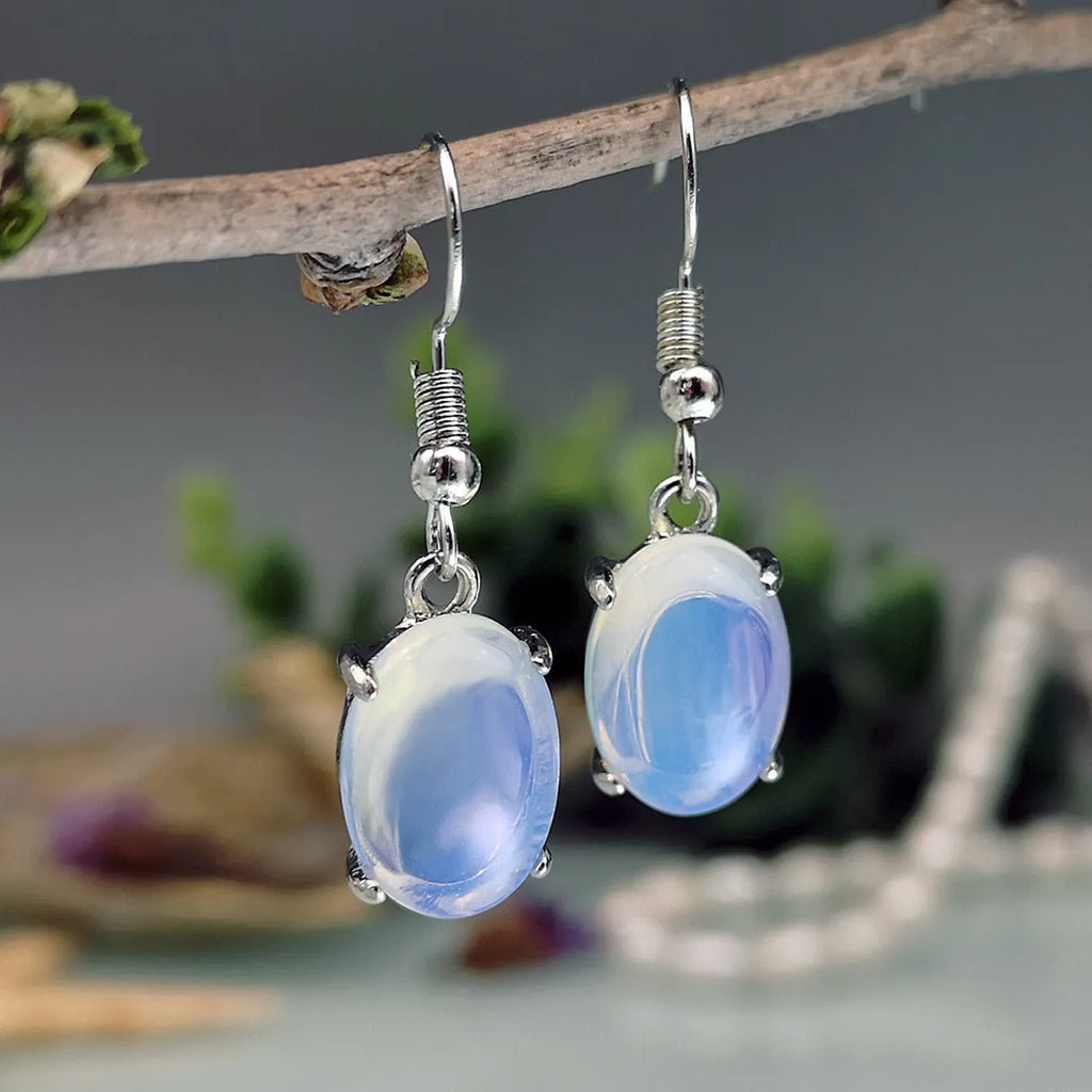 A pair of retro opal earrings with a moonstone eardrop and cross design in electroplated alloy.