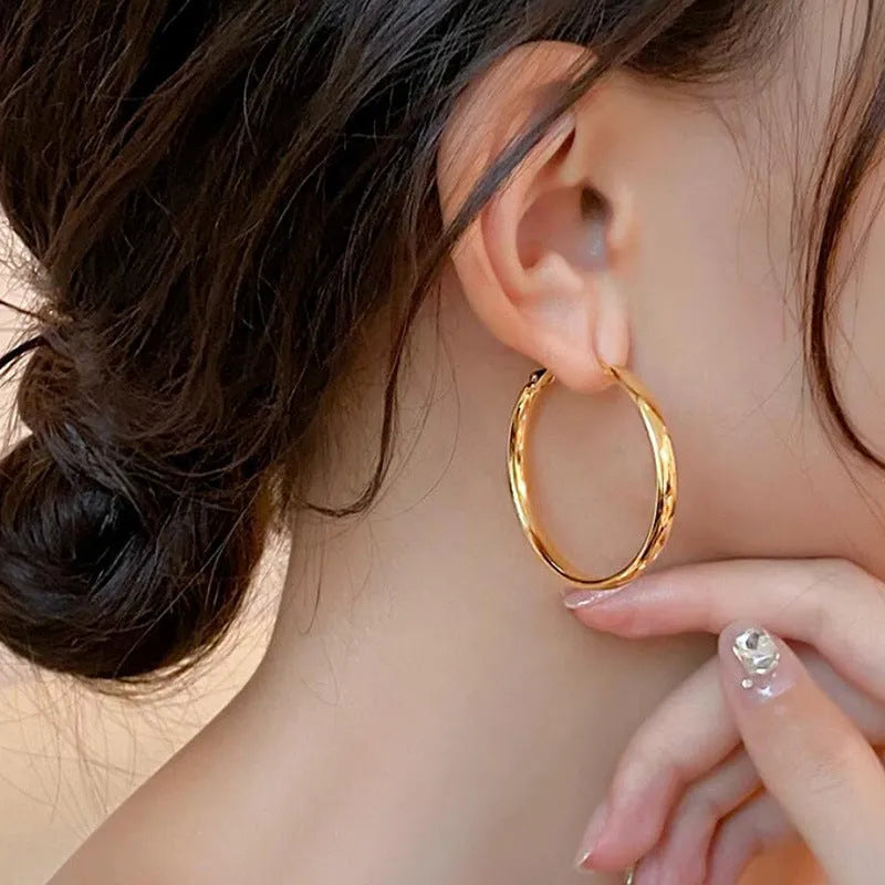 A pair of large gold-coloured circular metal earrings with a 40mm diameter on a white background.