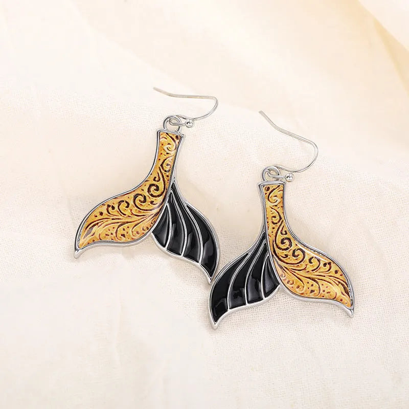 Close-up of women's retro fishtail earrings with a whale design in white gold colour.