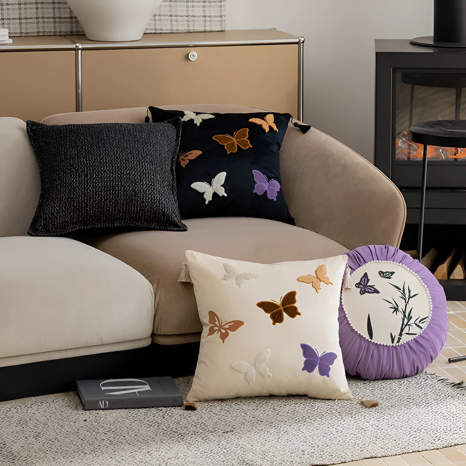 Square decorative cushion with embroidered butterfly pattern in beige, black, or purple colours.