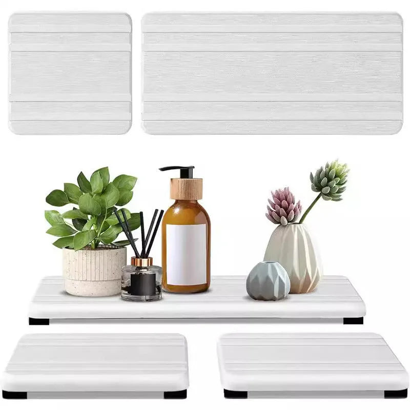 Set of three square diatom oil water draining pads in dark gray, light gray, and white on a bathroom countertop