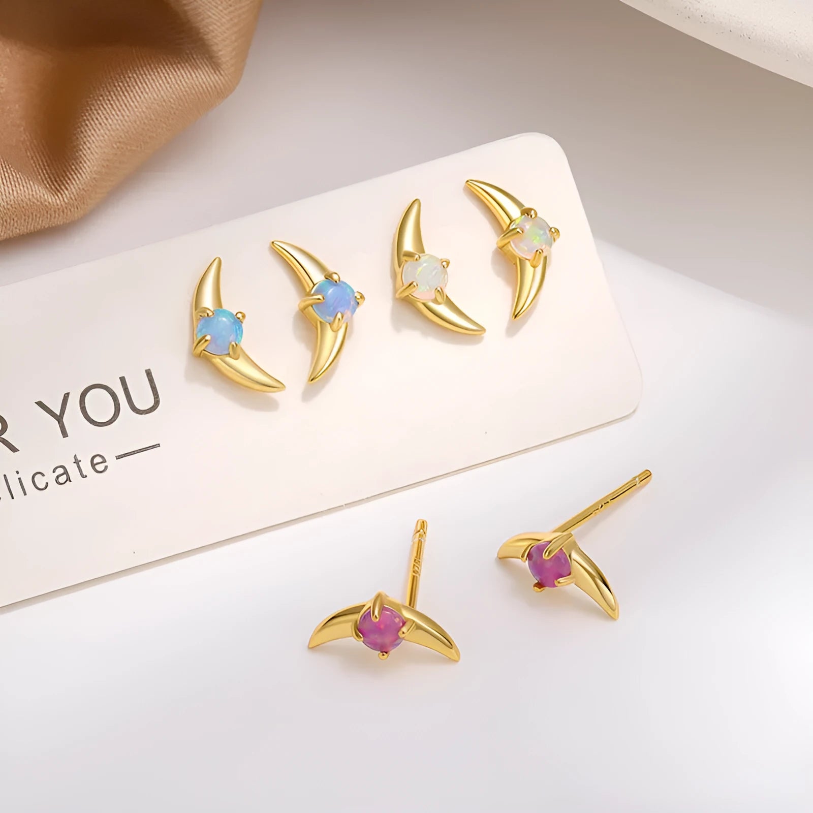 A pair of women's geometric earrings made from 925 silver, shown in gold plating with a blue stone accent.