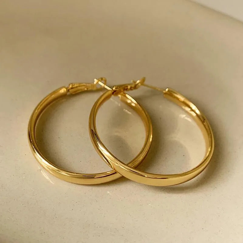 A pair of large gold-coloured circular metal earrings with a 40mm diameter on a white background.