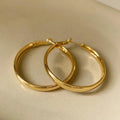 A pair of large gold-coloured circular metal earrings with a 40mm diameter on a white background.