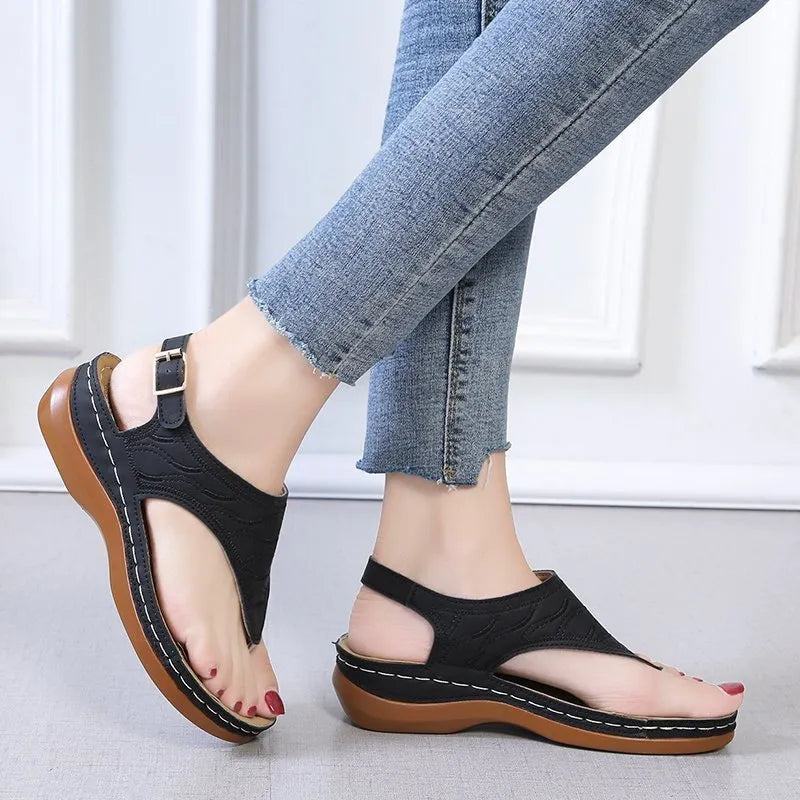 Women's black wedge heel sandals with an adjustable buckle strap on a light background.