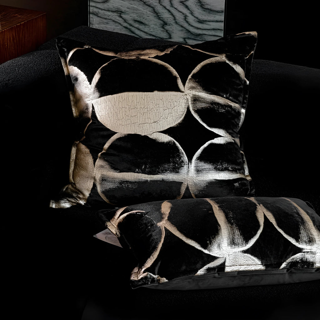 Black gold abstract patterned flannel decorative cushion on a sofa.
