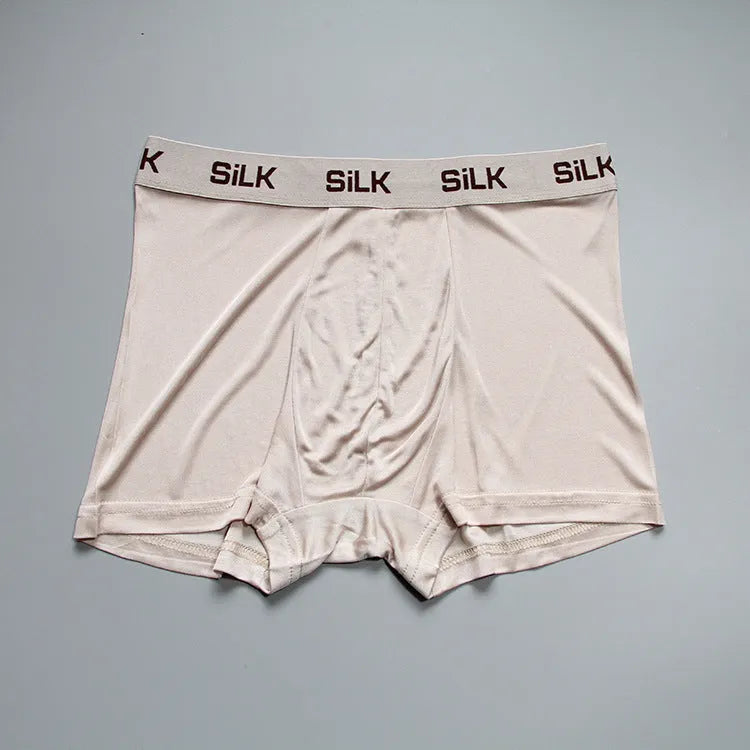 Men's loose-fit silk shorts in navy blue on a mid-waist, showing casual style.