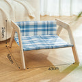 Elevated wooden cat bed with blue cloth hammock surface on a wooden floor