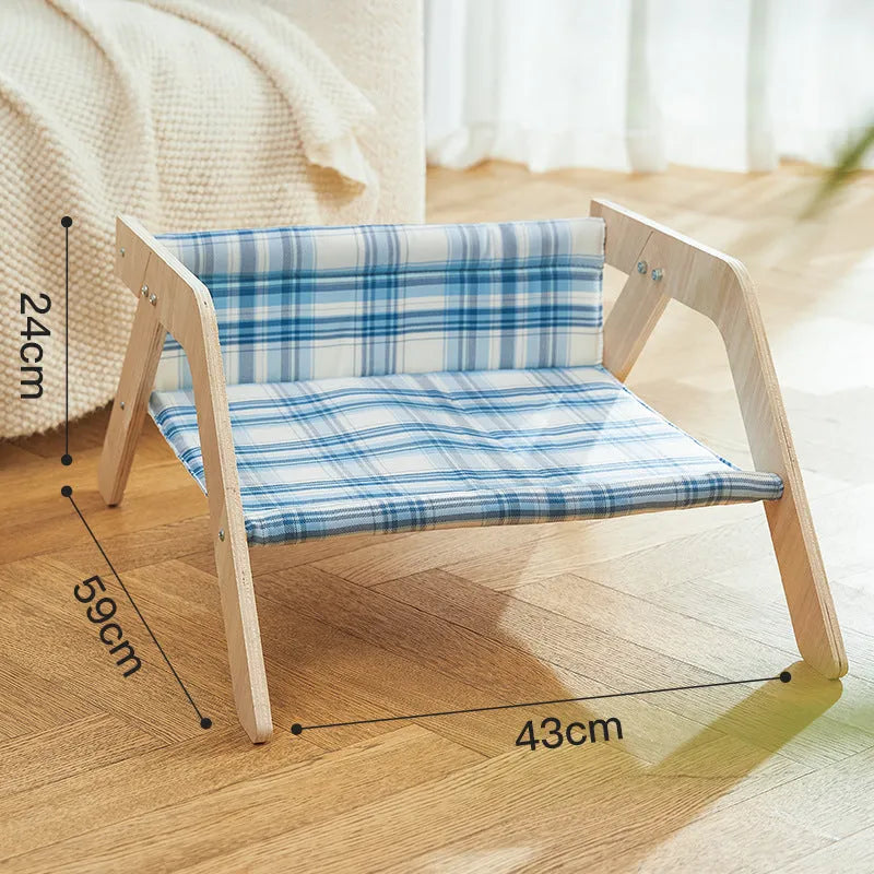 Elevated wooden cat bed with blue cloth hammock surface on a wooden floor
