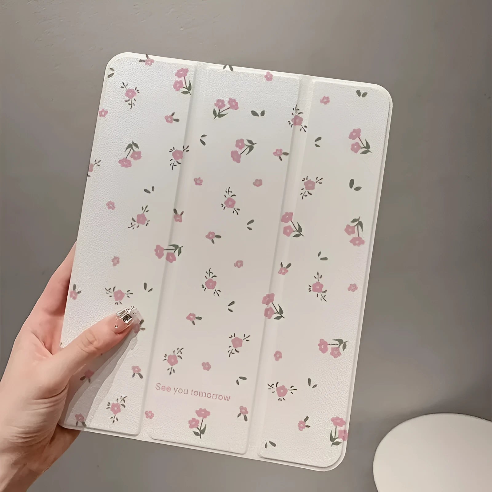 Transparent floral tri-fold hard case for iPad showing magnetic closure and stylus loop.