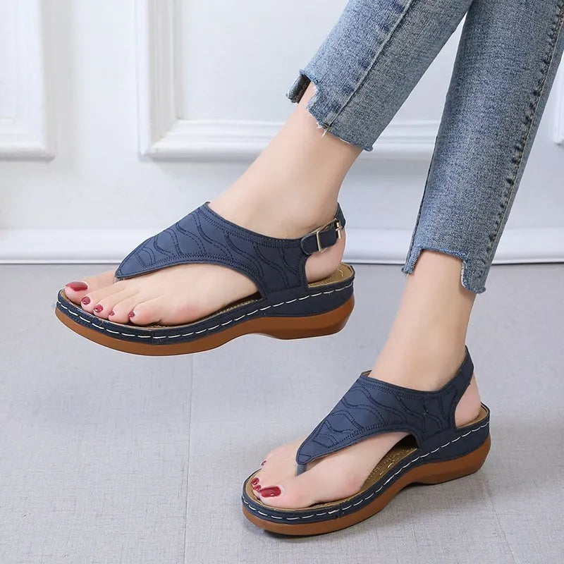 Women's black wedge heel sandals with an adjustable buckle strap on a light background.
