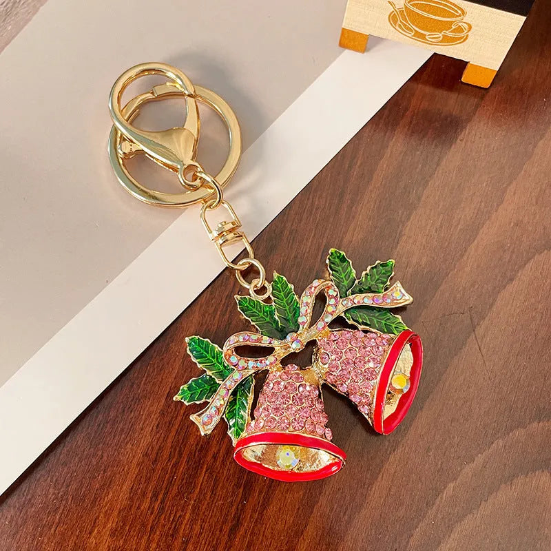 Christmas bell shaped metal keychain with diamond studded surface in champagne colour on white background