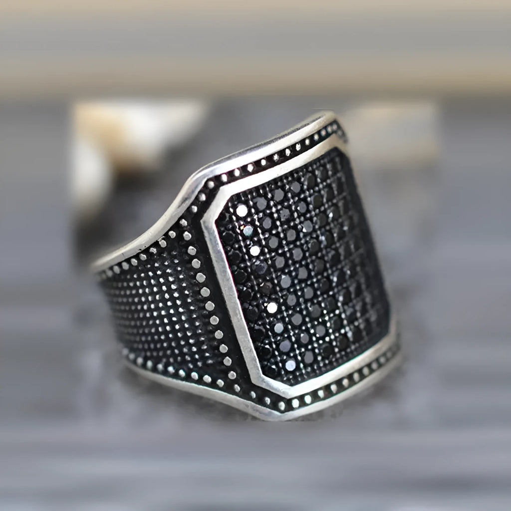 Black alloy ring with copper inlay and zircon stone, shown in unisex sizes 7 through 13.