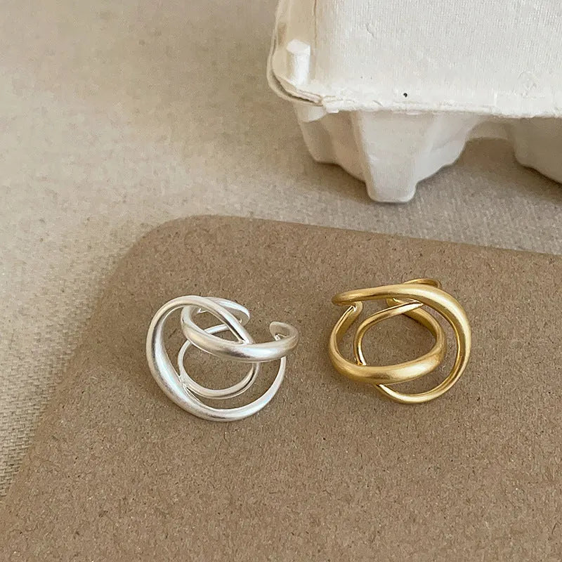 Geometric open ring for women with three-dimensional interlaced matte metal design in gold or silver.