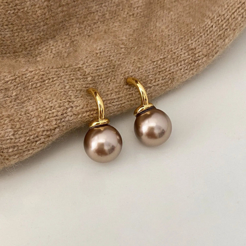 Vintage champagne pearl clip-on earrings with copper electroplated geometric design, on display as a pair