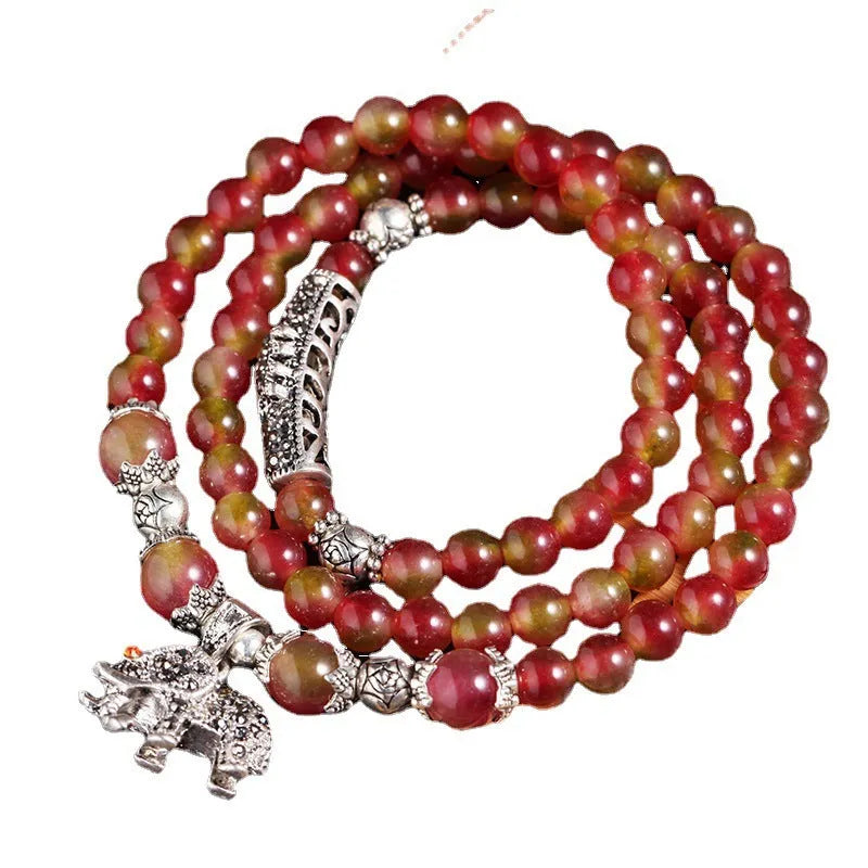 Close-up of a handmade watermelon crystal bracelet with a central Chinese knot and geometric beads.