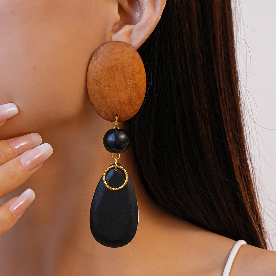 A pair of handcrafted wooden earrings with an elliptical shape in a silver, brown, and black colour finish.