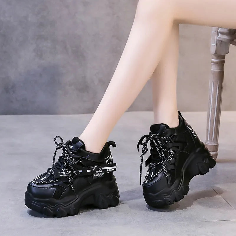 White and black women's low-top platform sports shoes with cross-strap and mesh design on a rubber sole.