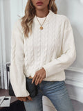 Women's loose beige pullover sweater with a twist detail and round neck on a hanger.