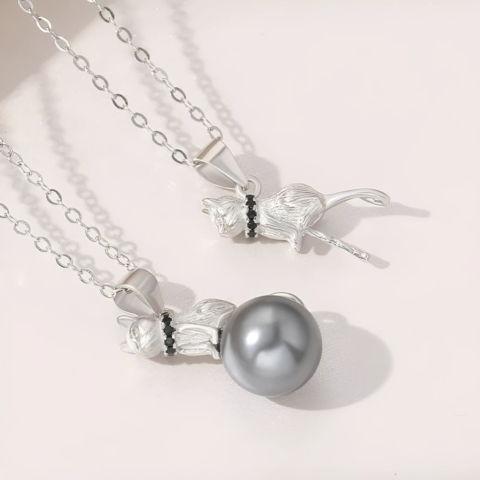 Close-up of a sterling silver cat pendant on a delicate clavicle chain necklace.